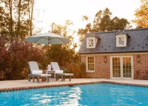 Two poly chaise lounges with side table and umbrella beside pool