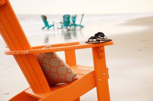 Orange poly adirondack chair with seat cushion at the beach