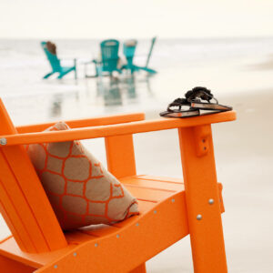 Orange poly adirondack chair with seat cushion at the beach