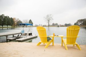 Two Yellow Poly Adirondack Chairs overlooking Lake