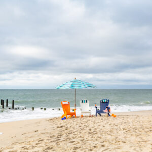Poly Adirondack Chairs and umbrella with ocean backdrop.