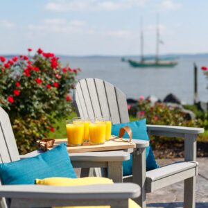 Two Great Bay Dining Chairs with a Great Bay Table Attachment on a dock by the ocean.