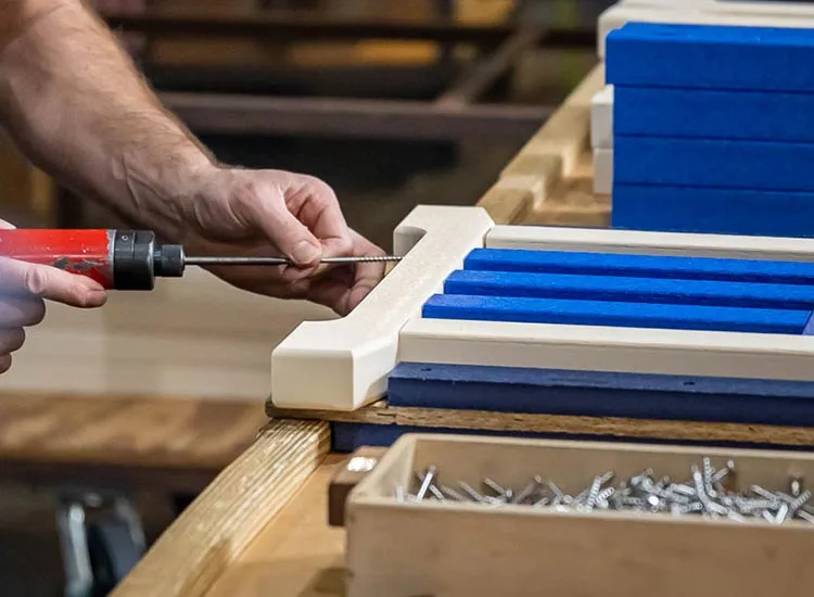 man inserting screw into finch poly table leg