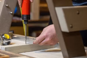 finch craftsman screwing a screw into the bottom of a finch poly bench