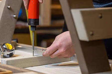 finch craftsman screwing a screw into the bottom of a finch poly bench
