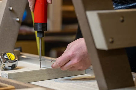 finch craftsman screwing a screw into the bottom of a finch poly bench