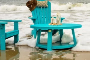 finch poly adirondack chairs and table on beach with the surf washing around the chairs.