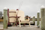 Two polly chairs sitting on the dock with fishing rods propped up against the chairs.