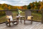 Two rockers sitting on a deck with autumn colors in the background.