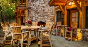 Great Bay Dining Furniture set on a patio by a log cabin in the woods