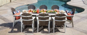 Great Bay Dining table and 8 chairs set up by a swimming pole with fruits and fruit punch on the table