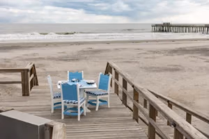 Wave Poly outdoor furniture set in ocean blue and white poly on a wooden deck by the beach