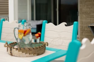 Finch Wave Chair and Table close up with sea turtle engraving on the chair back and a pitcher of water on the table