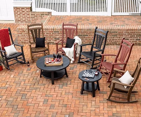 high tide poly rockers and seaaira round coffee tables on a brick patio
