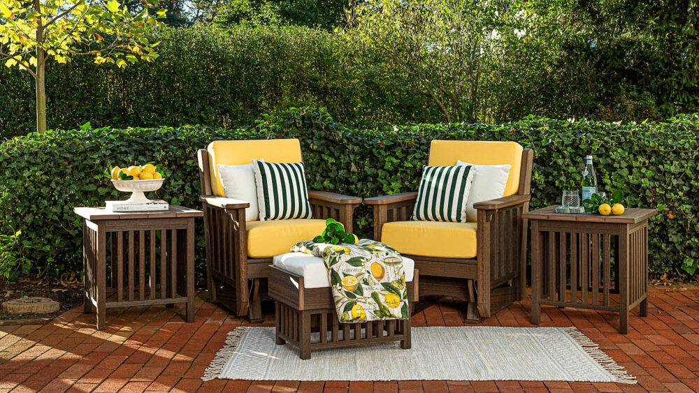 Two poly rockers sitting on a red brick patio with greenery in the background.