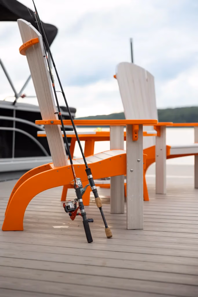 Two poly chairs sitting on a dock beside a boat.