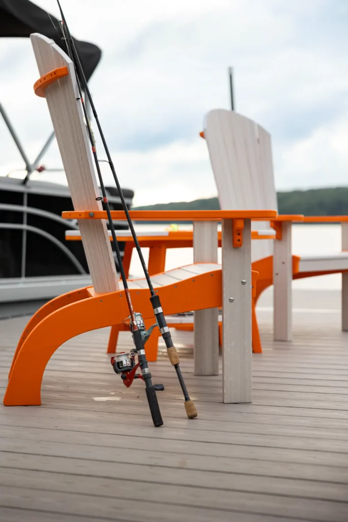 Two poly chairs sitting on a dock beside a boat.