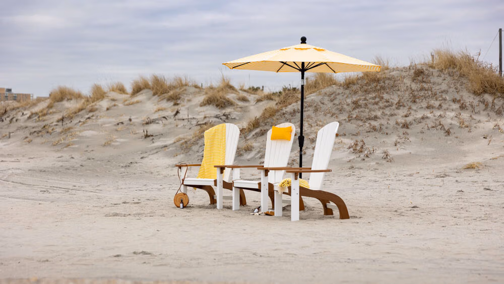 3 poly chairs sitting on the beach. 