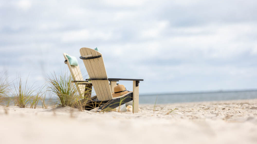 Two poly chairs sitting on the beach, facing the ocean.