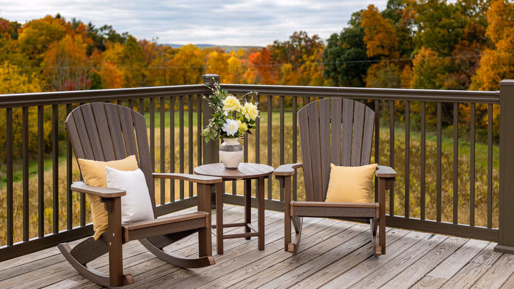 Two rockers sitting on a deck with autumn colors in the background. 