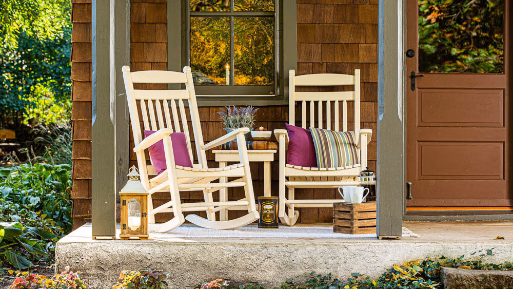 Two rockers sitting on a rustic cabin's porch. 