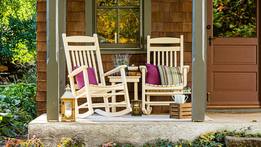 Two rockers sitting on a rustic cabin's porch.